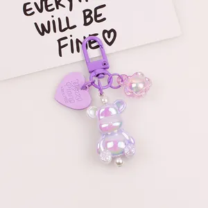 Detailed close-up of a holographic purple bear charm with white pearls and flower