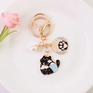 Close-up of black cat enamel keychain with moon, paw pendant and white pearl detail