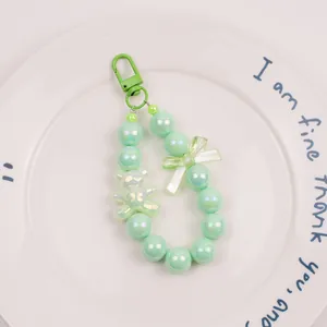 Detail of mint green beaded keychain with pearl-finish beads and cute bear pendant