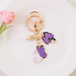 Detail of golden keychain with purple butterfly cat charms and a small white pearl