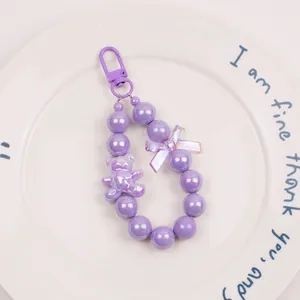 Macro shot of purple beaded keychain with a cute bear pendant and iridescent bow