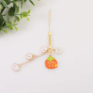 Gros plan de la dragonne dorée avec breloque kaki orange et pendentif nuage blanc