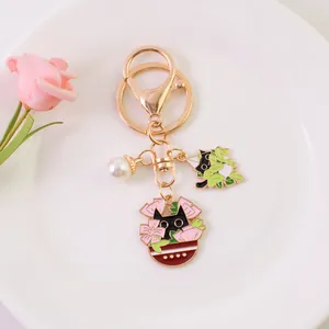 Detailed close-up of a golden cat keychain with enamel pendants and a white pearl charm