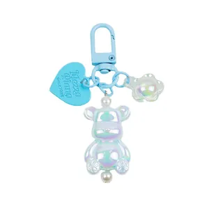 Luminous teddy bear keychain with iridescent heart charm and blue floral detail