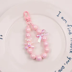 Detail of pink pearlescent beaded keychain with bear charm and bow decoration
