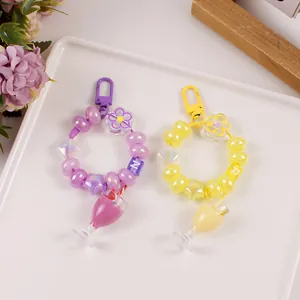 Detail of handmade beaded keychains with mini milk tea cups and letter beads in purple and yellow
