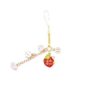 Pendentif de téléphone fraise créatif avec cordon doré et lettres sur fond blanc
