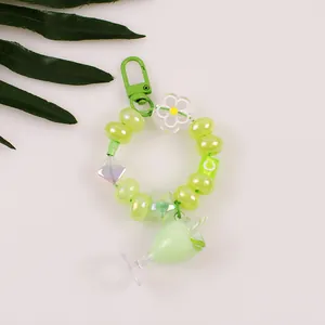 Detail of green acrylic bubble tea keychain with letter beads and floral charms