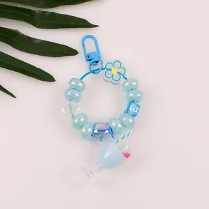Close-up of blue beaded keychain with letter E charm and miniature milk tea cup pendant