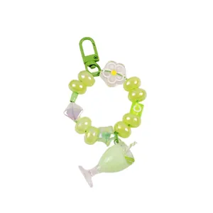 Green beaded keychain with milk tea cup charm and lettered blocks on white background