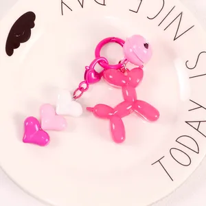 Close-up of pink jelly balloon dog keychain with heart charms on a decorative ceramic plate