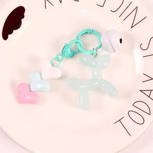 Detailed macro view of a translucent cyan balloon dog charm with heart beads and bell