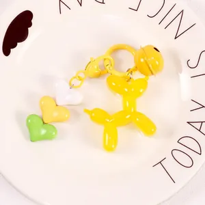 Detailed macro of yellow jelly balloon dog keychain with heart charms and matching bell