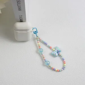 Detail of macaron beaded phone charm with a blue polka dot bow on an earphone case