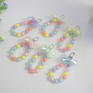 Close-up of six colorful macaron beaded charms with iridescent bows and lobster clasps
