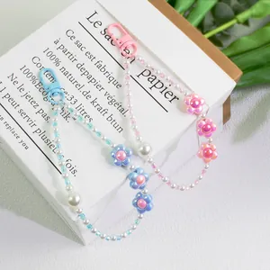 Detailed close-up of handmade pearl flower keychains with acrylic beads on white paper bag