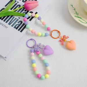Detail der bunten Macaron-Perlenkette mit Schleifen- und Herzanhänger auf weißem Grund