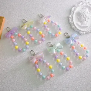 Macro shot of colorful macaron bead keychains with iridescent bows in six vibrant shades