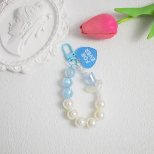 Dettaglio del ciondolo di perline azzurre con charm a tulipano e targhetta a cuore blu