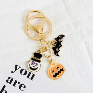 Detail of Halloween keychain with enamel skull, bat and pumpkin charms on white fabric