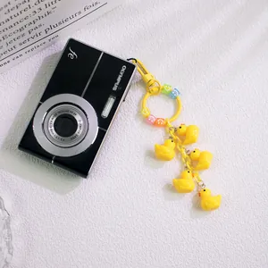 Cute yellow duck keychain with smiley face beads hanging on a vintage black camera