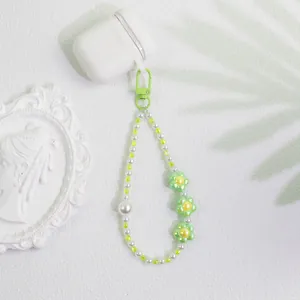 Detail of beaded keychain with green flowers and pearls for phone and bag decor
