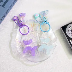 Detail of colorful balloon dog keychains with iridescent charms in a shell tray