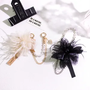 Close-up of feather flower keychain with pearls and heart metal pendant details
