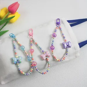 Detail of colorful beaded charms with polka dot bows and lobster clasps on a canvas bag