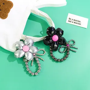Detail of puffed flower bag charms in silver and black leather with beaded butterfly accents