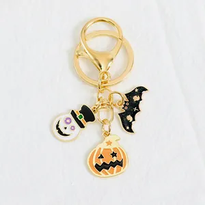 Halloween keychain with ghost pumpkin and bat charms on white fabric background