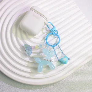 Blue resin balloon dog charm with rainbow and heart pendant on a white silicone earphone case