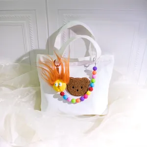 White canvas tote bag featuring cute cartoon plush charms and colorful beaded chain
