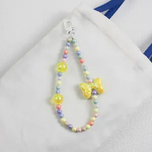 Detail of macaron beaded bag charm with large yellow bow and pastel colorful beads