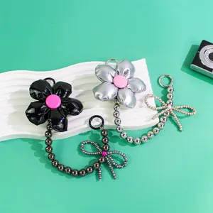 Detail of floral and bow bag charms featuring fluffy petals and pearl-beaded accents