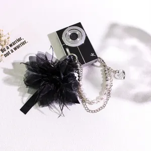 Detail of dark vintage feather keychain with black tulle flower and pearl chains