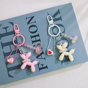 Detail of pink and cream balloon dog keychains with pearl collars and colorful charms