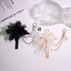 Detail of elegant feather flower keychain with pearl chain and heart metal charm