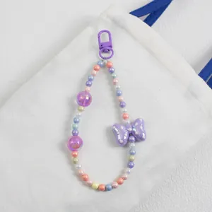Detail of beaded bag charm with purple polka dot bow and colorful acrylic beads