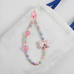 Close-up of colorful beaded bag charm with pink polka dot bow on white canvas bag