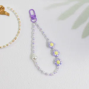 Detailed macro of sweet purple flower charms and pearl beads on a mobile phone strap