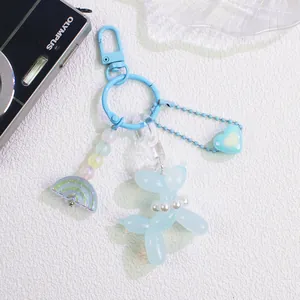 Detail of light blue balloon dog keychain with rainbow and heart charms on textured base
