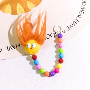 Close-up of a cartoon fuzzy keychain with colorful beads and fluffy orange hair detail