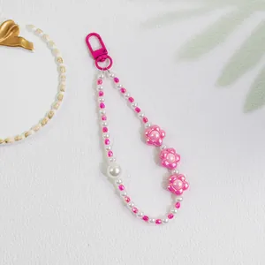 Detailed view of pink flower bead keychain with pearls and pink spring clasp on white tray