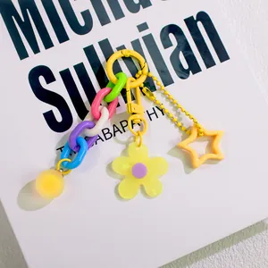 Detail eines bunten Acryl-Blumen-Schlüsselanhängers mit gelber Kette auf Buch