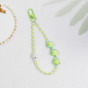 Detail of sweet flower keychain with white faux pearls and green floral pendants
