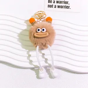 Close-up of plush monster keychain with big eyes, orange details and white shoes