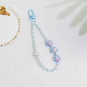 Detail of beaded keychain featuring blue flowers and pearls with a matching plastic hook