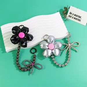 Detail of fluffy black and silver flower keychains with pink buttons and beaded bows