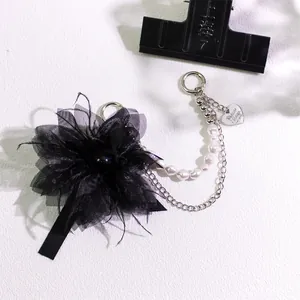 Detail of black feather flower accessory with faux pearl chain and heart metal charm